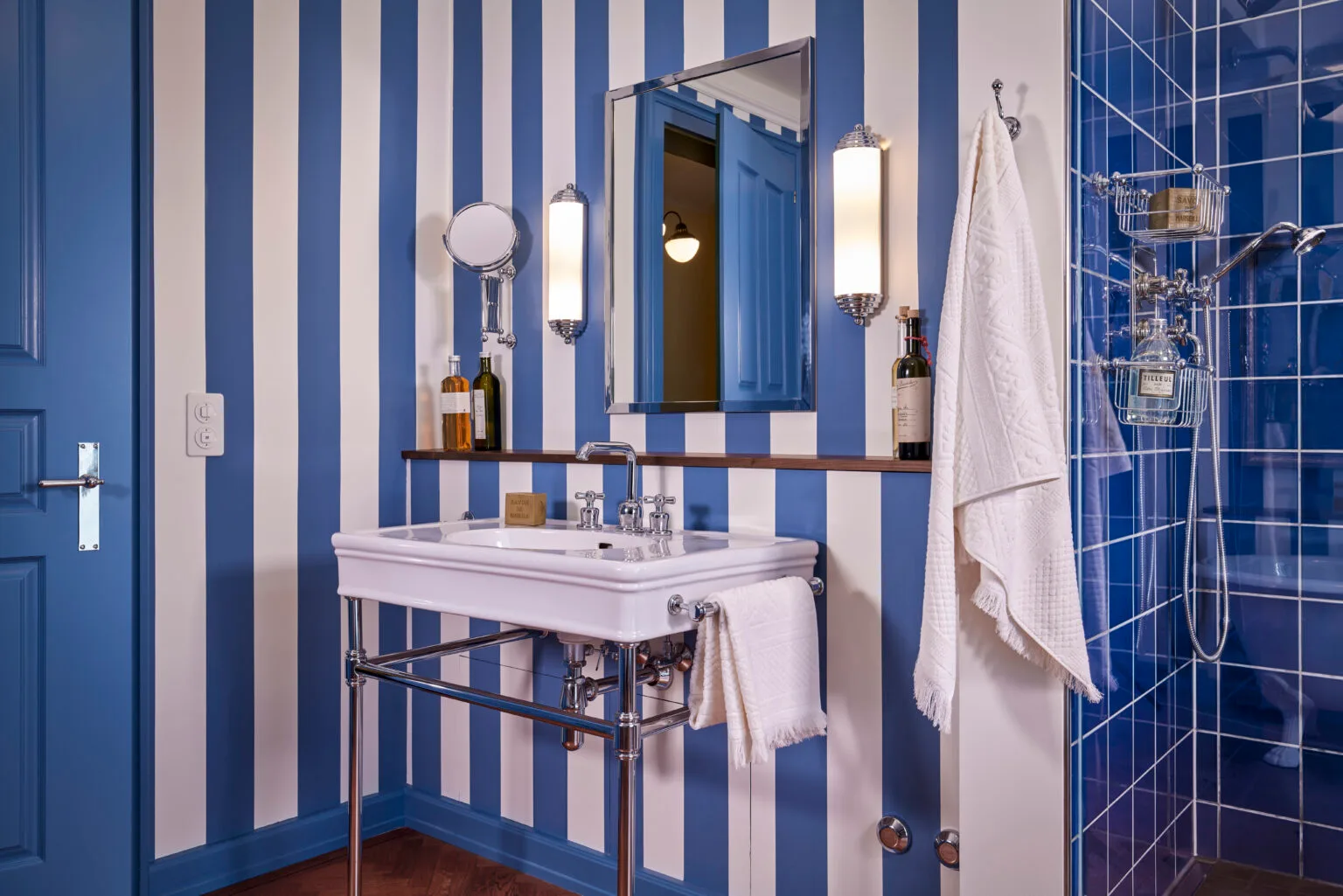 Blaues Badezimmer im Art-Deco Stil mit hochwertigen Accessoires massivem Spiegel und Duscharmaturen